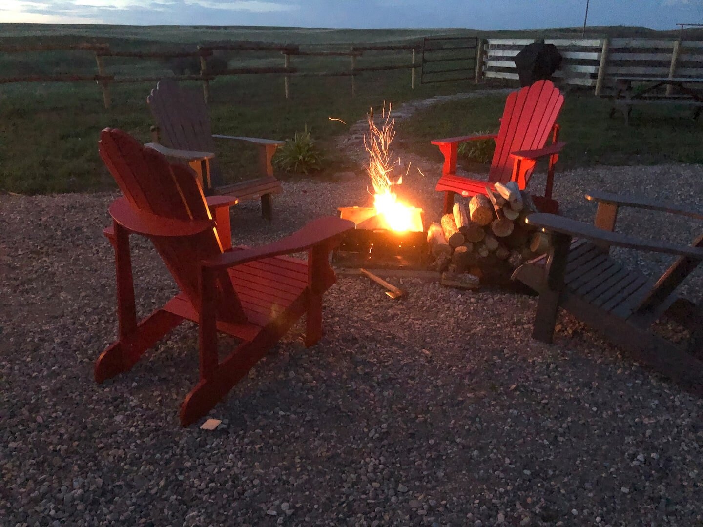 Firepit with Adirondack chairs between the cabins